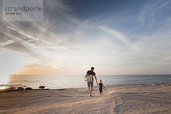 Erwachsener Mann  der mit seiner kleinen Tochter am Strand bei Sonnenuntergang spazieren geht  Calvi  Korsika  Frankreich