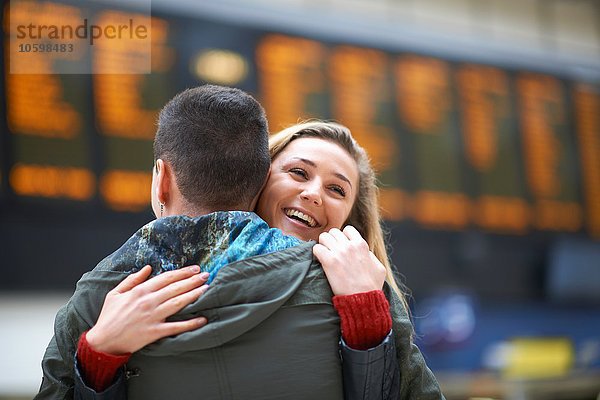 Heterosexuelle Paarumarmung am Bahnhof  Rückansicht