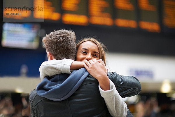 Heterosexuelle Paarumarmung am Bahnhof  Rückansicht