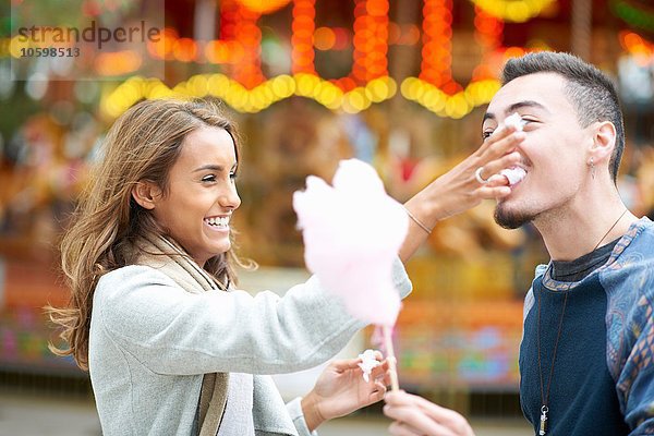 Junges Paar  herumalbern  Zuckerwatte essen auf dem Jahrmarkt  im Freien