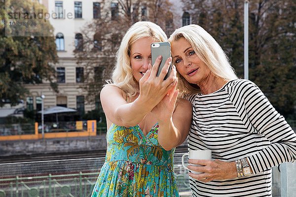 Frauen im Freien mit dem Smartphone zu nehmen Selfie lächeln