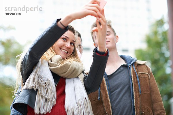 Junge Frau  die Smartphone Selfie mit männlichen Freunden nimmt