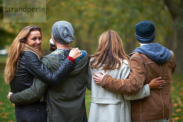 Rückansicht zweier junger Paare beim Spaziergang im Herbstpark