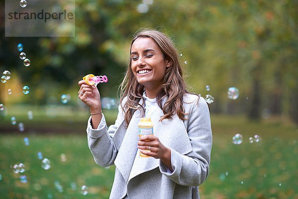 Junge Frau beim Blasenblasen im Herbstpark