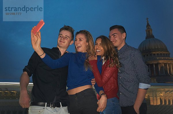 Zwei junge Paare mit Smartphone-Selfie vor St. Pauls bei Nacht  London  UK