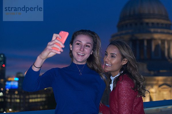 Zwei junge Frauen mit Smartphone-Selfie vor St. Pauls bei Nacht  London  UK
