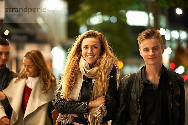 Zwei junge Paare schlendern Arm in Arm entlang der Straße bei Nacht  London  UK