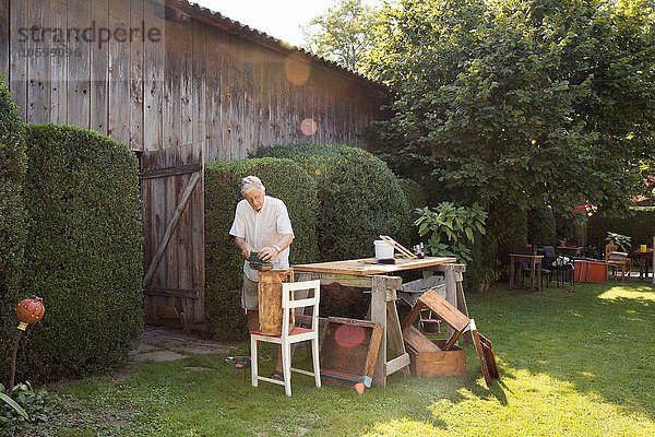 Senior Mann macht Holzkiste im Garten
