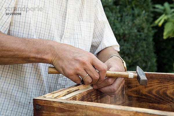 Senior Mann macht Holzkiste im Garten  Mittelteil