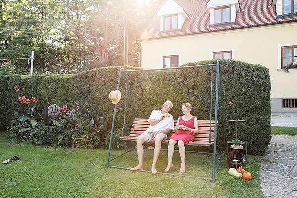 Seniorenpaar  entspannt auf dem Schaukelsitz im Garten