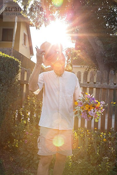 Senior Mann im Garten  hält einen Strauß frischer Schnittblumen.