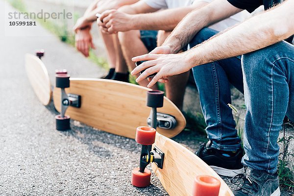 Junge Männer sitzend mit Skateboards