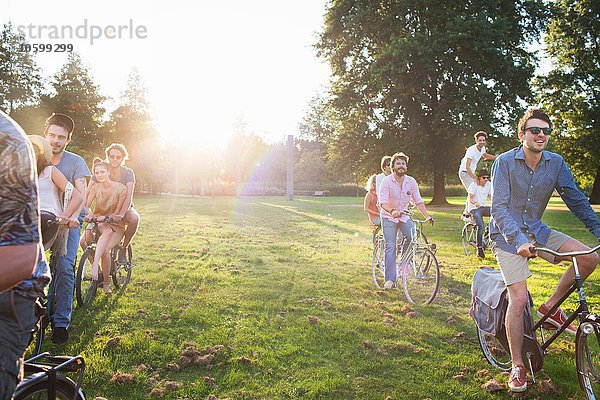 Reihen von Erwachsenen  die bei Sonnenuntergang mit dem Fahrrad im Park ankommen.
