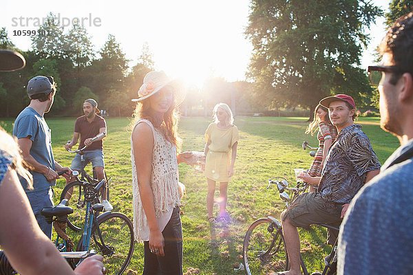 Gruppe von Erwachsenen  die bei Sonnenuntergang mit dem Fahrrad im Park ankommen.