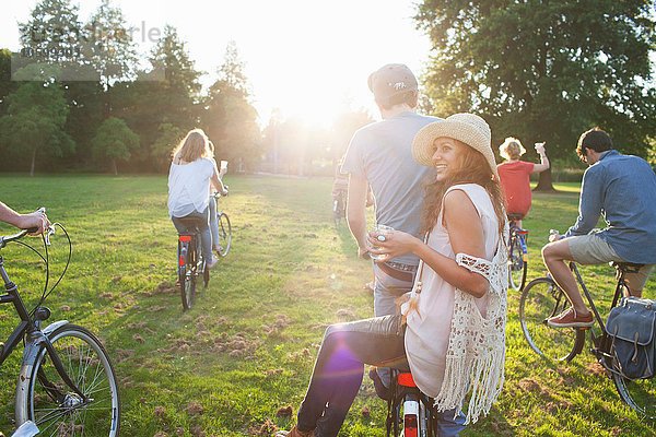 Rückansicht der Party für Erwachsene im Park auf Fahrrädern bei Sonnenuntergang