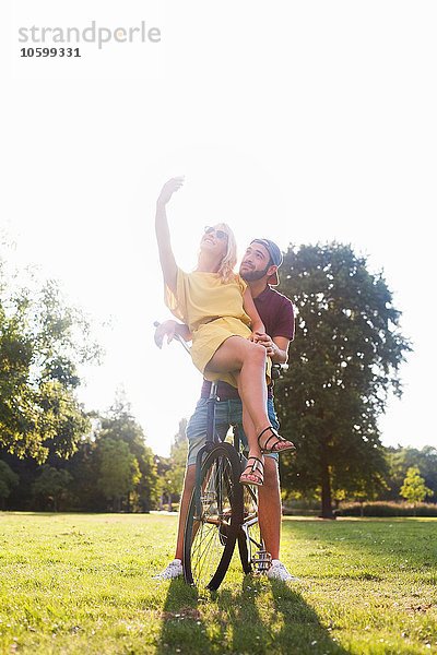 Junges Paar auf dem Fahrrad mit Smartphone Selfie im sonnigen Park