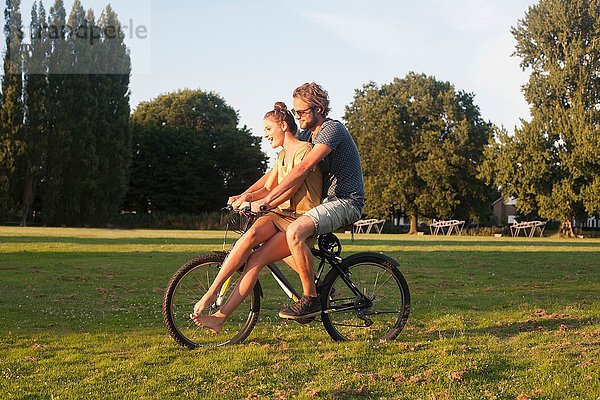 Romantisches junges Paar auf dem Fahrrad zusammen im Park
