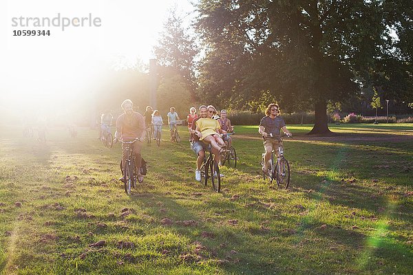 Massen von erwachsenen Freunden  die mit dem Fahrrad zum Sonnenuntergang anreisen.