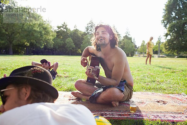 Erwachsene Freunde spielen Akustikgitarre auf der Sunset Park Party