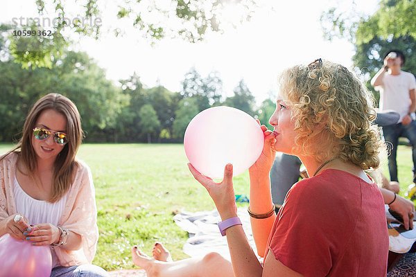 Junge Frau beim Aufblasen des Ballons auf der Parkparty