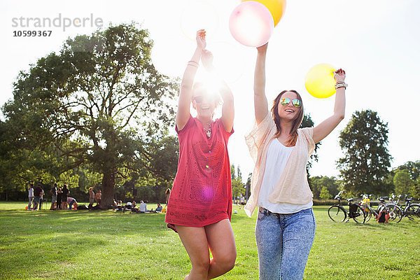 Zwei junge Frauen tanzen mit Luftballons auf der Parkparty