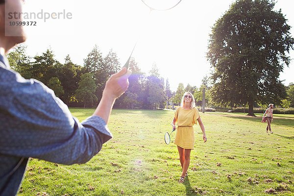 Junges Paar spielt Badminton im sonnigen Park