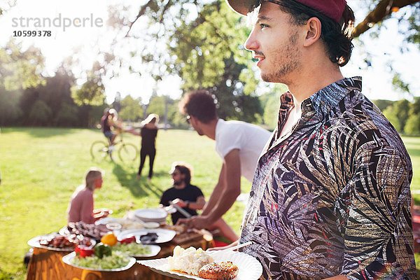 Junger Mann mit Picknickteller auf der Parkparty