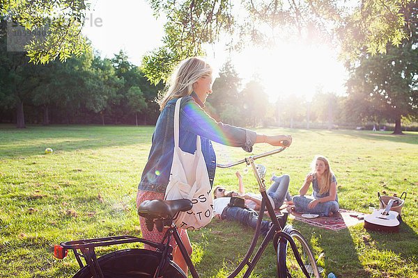 Junge Frau kommt mit dem Fahrrad zur Sunset Park Party