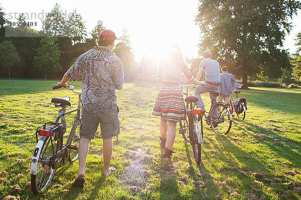 Rückansicht der erwachsenen Partygäste  die mit dem Fahrrad zur Sunset-Park-Party anreisen