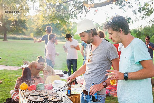 Junge Männer beim Grillen auf der Gruppenparty im Park