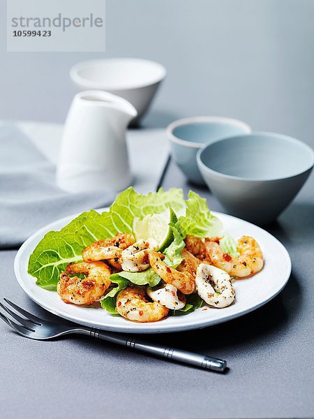 Tandoori-Garnelen und gegrillte Calamari mit Limettenscheibe und Kopfsalat