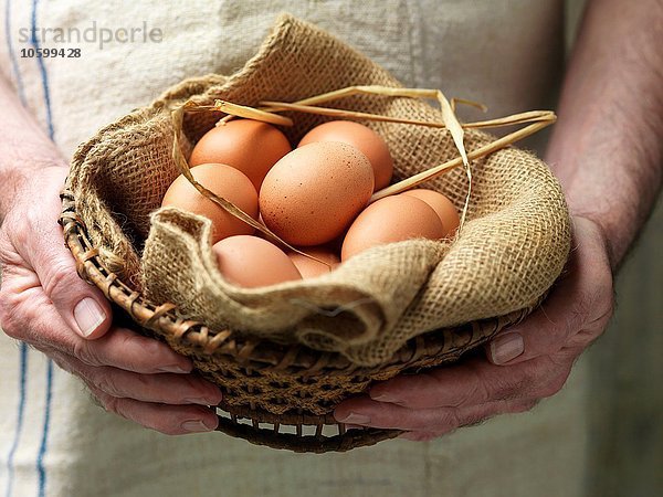 Seniorin mit Eiern in Vintage-Tuch und Korb