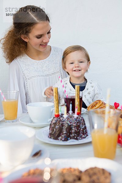 Teenagermädchen und Kleinkind am Verandatisch zur Geburtstagsfeier