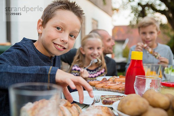 Portrait von Junge und Familie am Gartengrilltisch