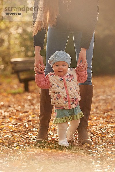 Porträt eines Mädchens  das Mütterhände im Herbstpark hält.