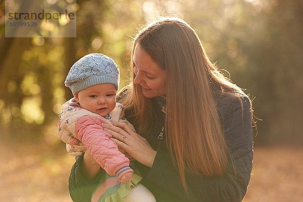 Mittlere erwachsene Frau und kleine Tochter mit Blick in den Herbstpark