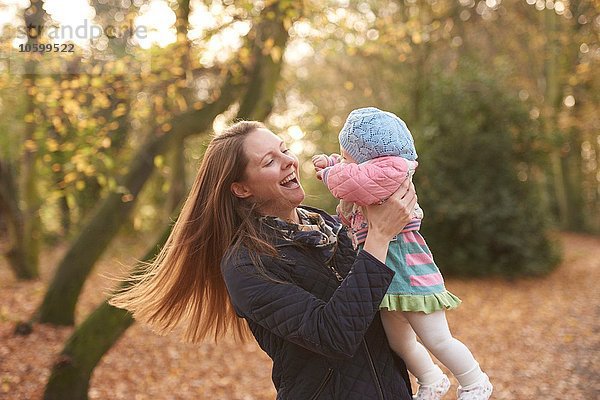 Mittlere erwachsene Frau schwingende kleine Tochter im Herbstpark