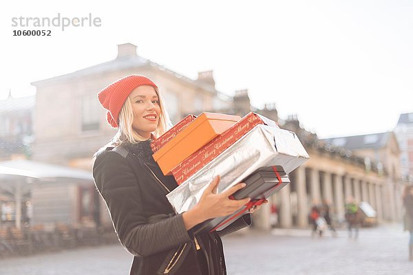 Portrait einer stilvollen jungen Frau mit einem Stapel Weihnachtsgeschenke  Covent Garden  London  UK