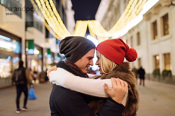 Romantisches junges Paar  das sich an Weihnachten auf der Straße umarmt  London  UK