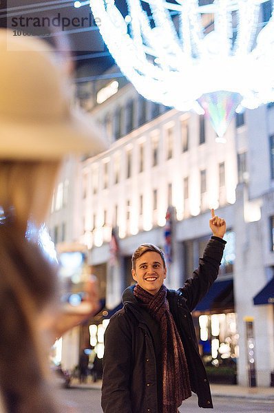 Junges Paar zeigt auf Weihnachtsbeleuchtung in der New Bond Street  London  UK