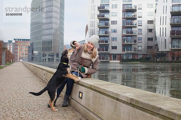 Mittlere erwachsene Frau füttert ihre Hundesnacks an der Uferpromenade