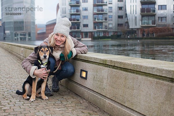 Porträt einer erwachsenen Frau und ihres Hundes am Flussufer der Stadt