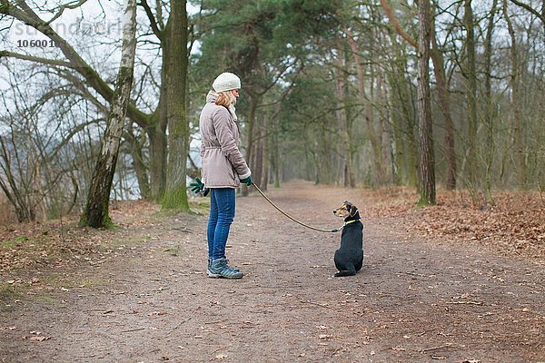 Mittlere erwachsene Frau und ihr Hund im Wald