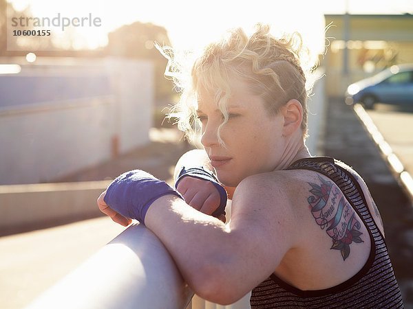 Porträt einer jungen Boxerin  die sich an ein städtisches Geländer lehnt.