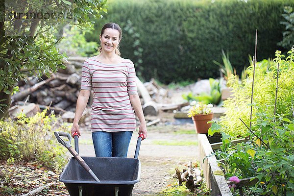 Porträt einer Gärtnerin beim Schubkarrenschieben im rustikalen Bio-Garten