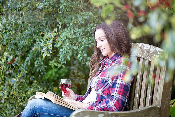 Mittlere erwachsene Frau beim Lesen auf der Gartenbank im Thornbury Castle  South Gloucestershire  UK