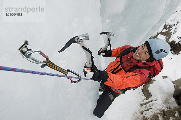 Junger Mann beim Eisklettern  lächelnd