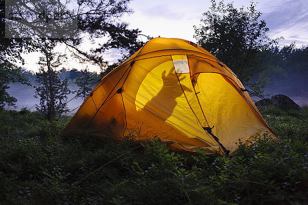 Beleuchtetes Zelt in nebliger Landschaft