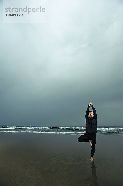 Mann macht Yoga am Strand