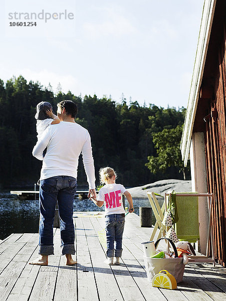 Vater mit zwei Töchtern beim Spaziergang auf dem Bootssteg